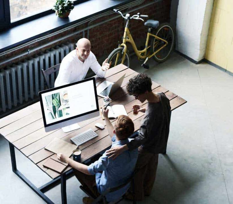 Drive Business Growth With IT Consulting Services That Put People First Professionals gathered around a table, engaged with a computer, focusing on services for IT support in Fort Worth.