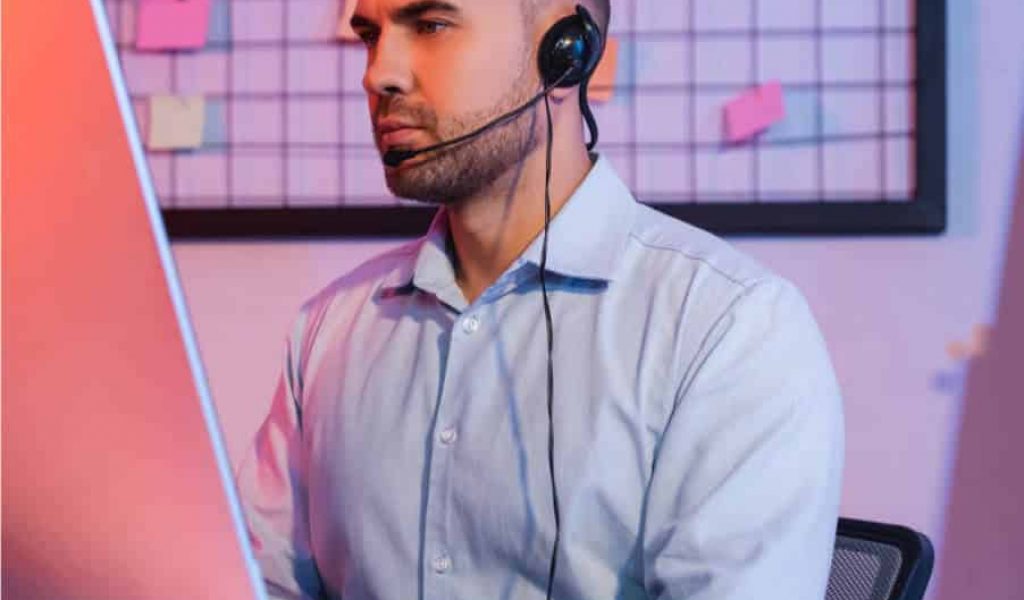 IT Helpdesk Services in Mississauga A man at a desk, equipped with headphones and a headset, is actively working at the IT Helpdesk Mississauga Services center.